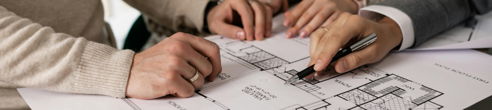 Personen besprechen einen Gebäudegrundriss als Grundlage für die Heizlastberechnung nach DIN EN 12831.